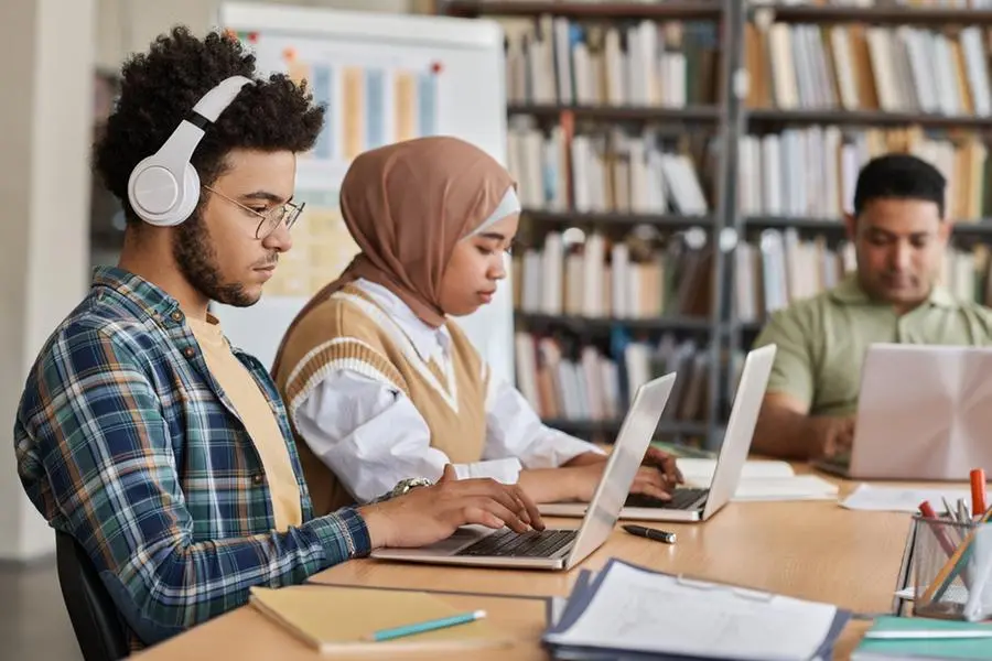 Group of foreign students using computers in their study while sitting at table in the library , Getty Images