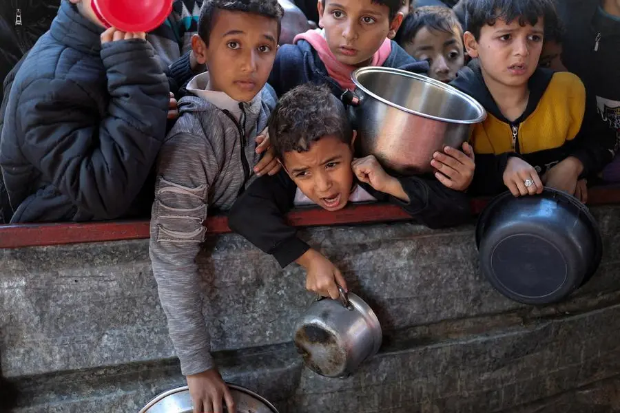 FILE PHOTO: Palestinian children wait to receive food cooked by a charity kitchen amid shortages of food supplies, as the ongoing conflict between Israel and the Palestinian Islamist group Hamas continues, in Rafah, in the southern Gaza Strip, February 5, 2024. REUTERS/Ibraheem Abu Mustafa/File Photo