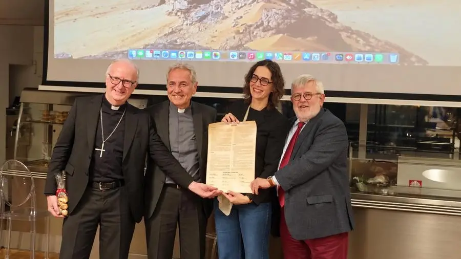 Insieme a Chiara Pelizzoni, giornalista e presidente dell’Associazione Per il Refettorio Ambrosiano, che mostra una copia del Patto «La via italiana del dialogo interreligioso. Le religioni nello spazio pubblico e per la coesione sociale», donata al Refettorio da don Giuliano Savina, direttore dell’Ufficio nazionale per l’Ecumenismo e il Dialogo interreligioso della CEI, in occasione dell’incontro «Ostinati nel dialogo».