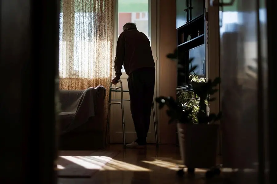 Un anziano con il deambulatore guarda fuori dalla finestra della sua abitazione. , Getty Images