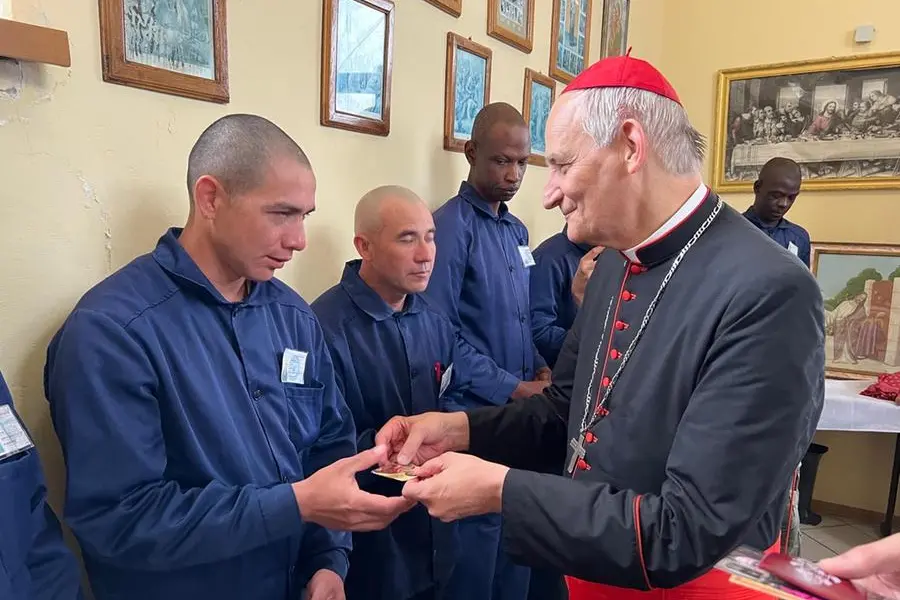 Zuppi consegna il dono del portachiavi a uno dei detenuti.