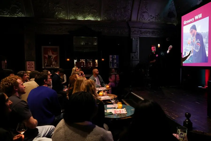 A participant shows a presentation during \\\"Date My Mate\\\", a live dating night where friends pitch their single friends, in north London, Britain, March 25, 2026. REUTERS/Isabel Infantes