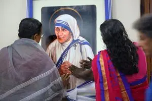 Alcuni fedeli di Calcutta pregano davanti al ritratto di Madre Teresa