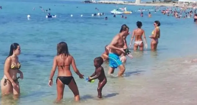 La figlia dell'ambulante accudita in spiaggia dalle mamme