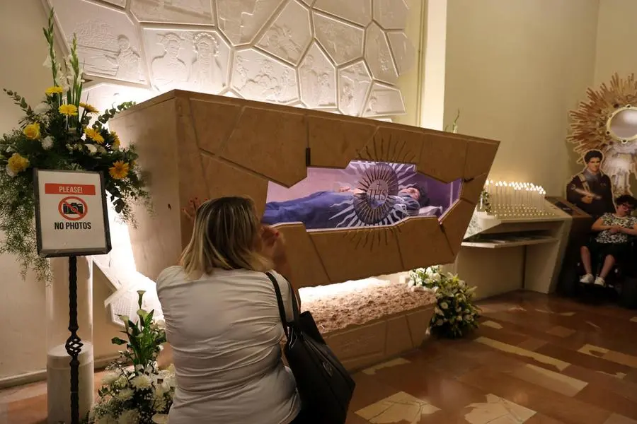 Fedeli in preghiera davanti alle spoglie mortali di San Carlo Acutis nel Santuario della Spogliazione di Assisi