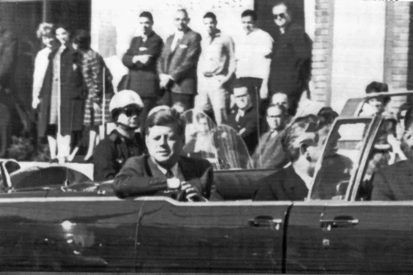 John Fitzgerald Kennedy a bordo della limousine presidenziale in Dealey Plaza a Dallas, poco prima di essere ucciso. ANSA / ARCHIVIO
