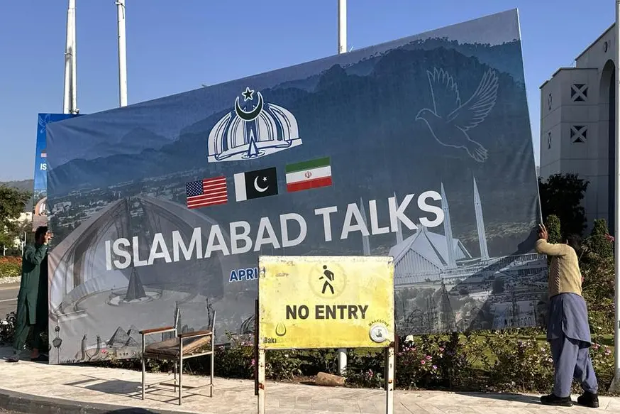Operai rimuovono i cartelloni a Islamabad, Pakistan, sui colloqui di pace falliti tra Usa e Iran (Epa/Ansa)
