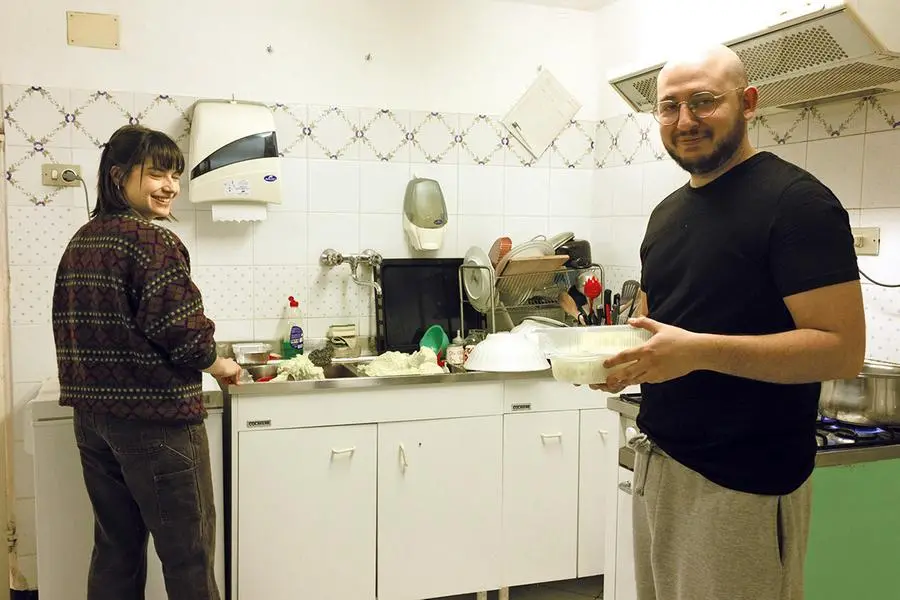 Simone Meneghelli, 31 anni, uno dei coordinatore di Young Caritas in cucina con un’altra volontaria.