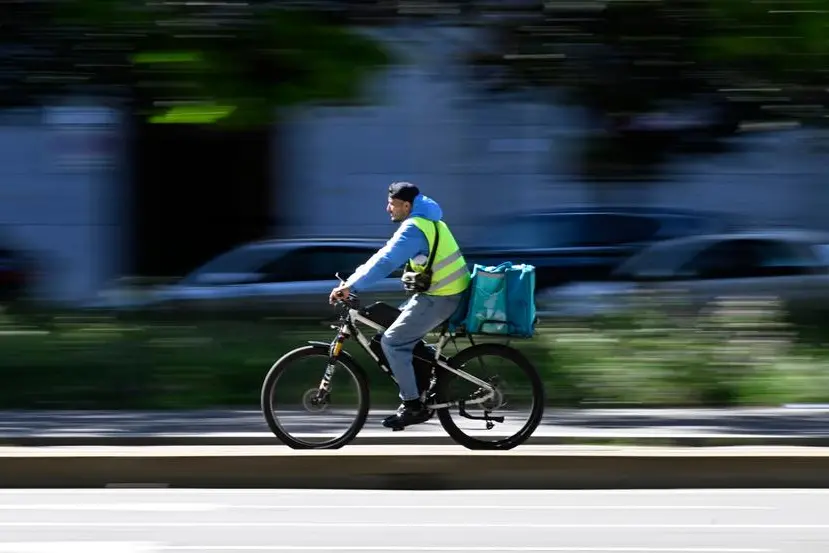Un rider effettua una consegna a Milano, 20 maggio 2026. Foodinho-Glovo, finita sotto controllo giudiziario per caporalato sui rider lo scorso febbraio, si \\u00E8 impegnata ad aumenti delle paghe per ogni consegna, portate fino ad un valore minimo di 3 euro lordi, e aumenti anche sui corrispettivi minimi orari lordi, da 10 fino a 14 euro, e il tutto per una crescita dei compensi mensili che potrebbe arrivare in media a circa 200 euro in pi\\u00F9. ANSA/DANIEL DAL ZENNARO , ANSA