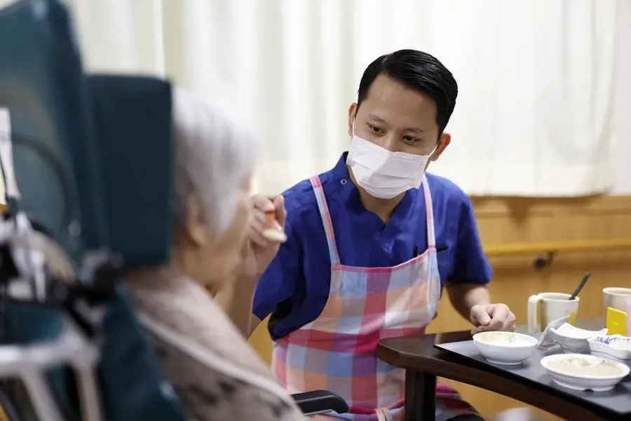 Un caregiver che assiste un\\'anziana , EPA