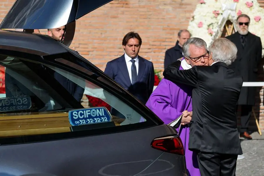 Giancarlo Giammetti embraces the priest at the end of the funeral