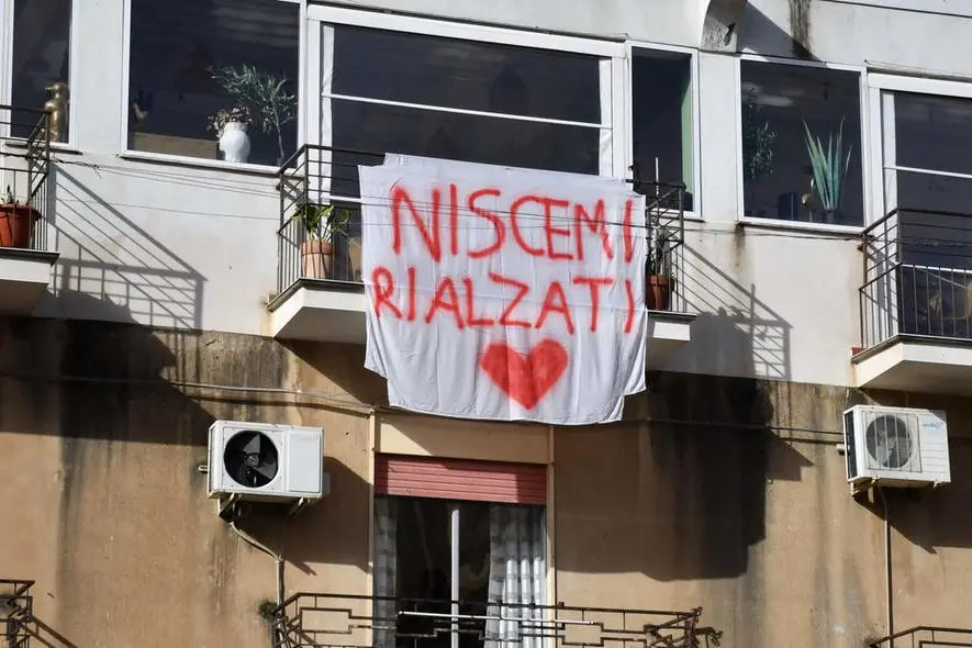 Uno striscione appeso sul balcone di un'abitazione a Niscemi, il paese in provincia di Caltanissetta colpito dalla frana, Niscemi, 28 gennaio 2026, ANSA/Orietta Scardino The banner \\\"Niscemi rise again\\\" hanging on the balcony of a house in Niscemi, the town in the province of Caltanissetta hit by the landslide. Niscemi, January 28, 2026, ANSA/Orietta Scardino