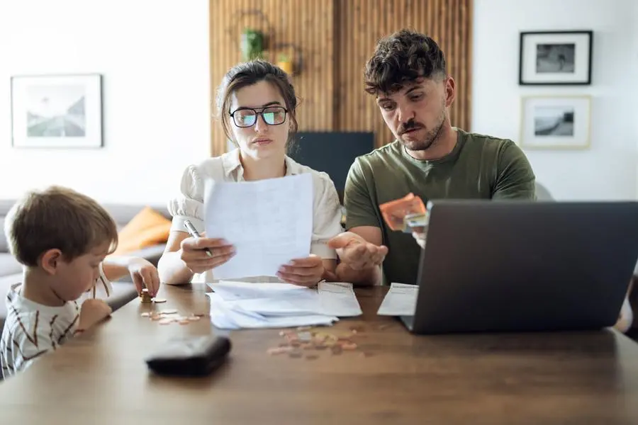 Una famiglia con un bambino piccolo alle prese con il bilancio domestico, tra bollette, tasse e spese mensili, in un periodo segnato dall\\u2019aumento del costo della vita , Getty Images