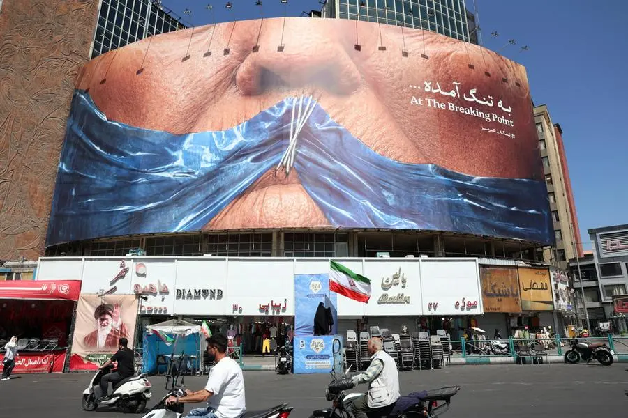 epa12946977 Iranians drive past a veiled woman holding Iran\\u2019s national flag in front of a huge anti-US billboard referring to US President Donald Trump and the Strait of Hormuz at Valiasr Square in Tehran, Iran, 11 May 2026. US President Donald Trump says Iran\\u2019s counter-proposal to end the ongoing conflict is not acceptable. EPA/ABEDIN TAHERKENAREH , EPA