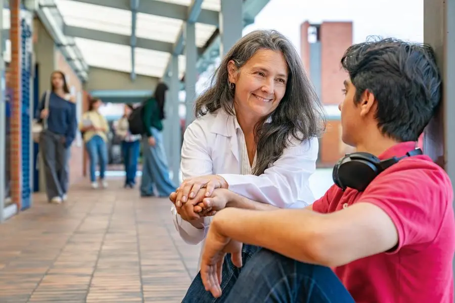Teacher talking to a student at the school corridor during his recess - education concepts , istock