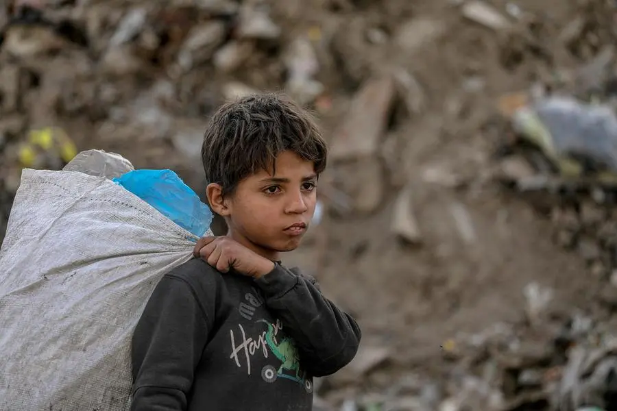 Un bambino a Gaza City che raccoglie plastica tra i rifiuti. , ANSA