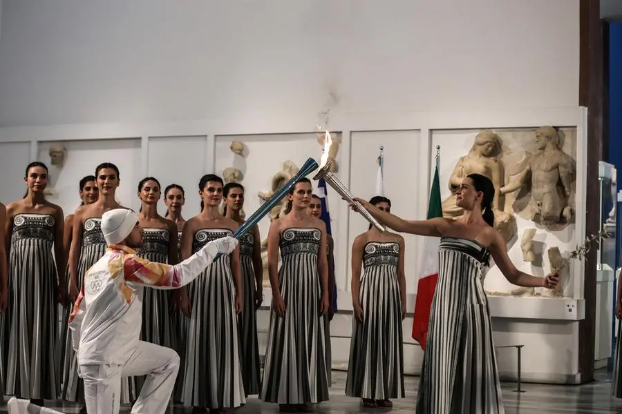 epa12549778 A handout photo made available by Presidency of the Hellenic Republic shows Greek actress Mary Mina (R), playing the role of High Priestess, passing the flame to the first torchbearer Petros Gaidatzis (L) during the Olympic flame lighting ceremony for the Milano Cortina 2026 Winter Olympics at the Archaeological Museum of Olympia, in southern Greece, 26 November 2025. The Milano Cortina 2026 Winter Olympics will be held from 06 February to 22 February 2026. EPA/THODORIS MANOLOPOULOS HANDOUT HANDOUT EDITORIAL USE ONLY/NO SALES