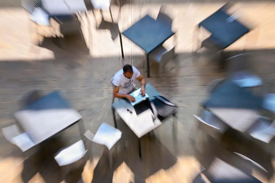 Tra i tavoli di un bar a Napoli un uomo lavora in \"smart working\", una delle parole pi\\u00F9 cercate su Treccani.it nel 2026. , ANSA