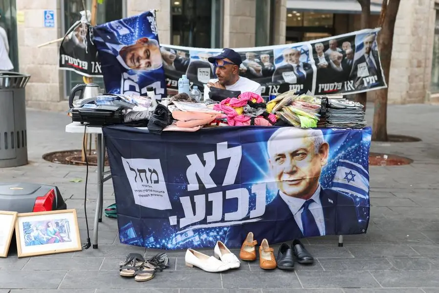 Un uomo vende oggetti di seconda mano su un tavolo circondato da manifesti elettorali del primo ministro israeliano Benjamin Netanyahu, leader del Likud, nel centro di Gerusalemme