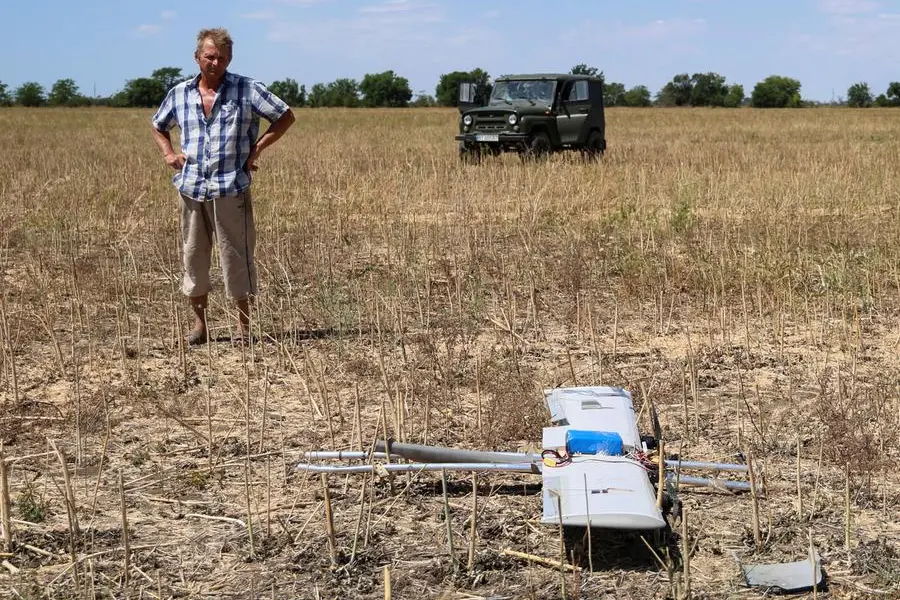 Un agricoltore osserva i resti di un drone russo caduto sul suo campo, nella regione di Kherson.
