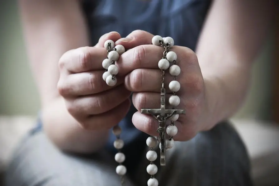 Una donna mentre recita il Rosario , Getty Images