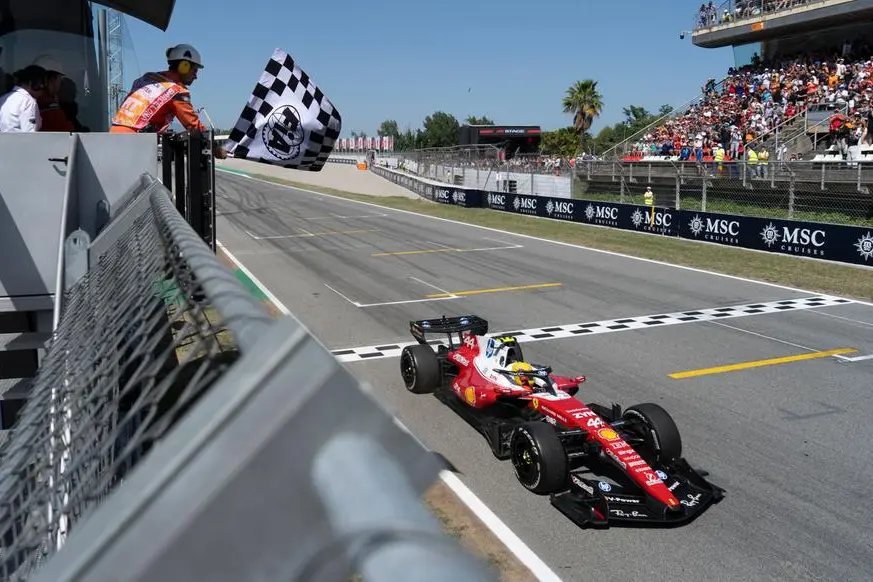 Lewis Hamilton al Gp di Spagna passa primo sotto la bandiera a scacchi sventolata da Novak Djokovic