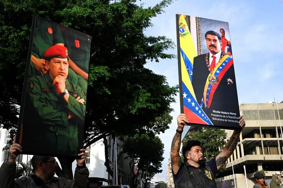 Government supporters hold photographs of Venezuela's late President Hugo Chavez and President Nicolas Maduro, after US President Donald Trump said the US has struck Venezuela and captured Maduro, in Caracas, Venezuela January 3, 2026. REUTERS/Maxwell Briceno