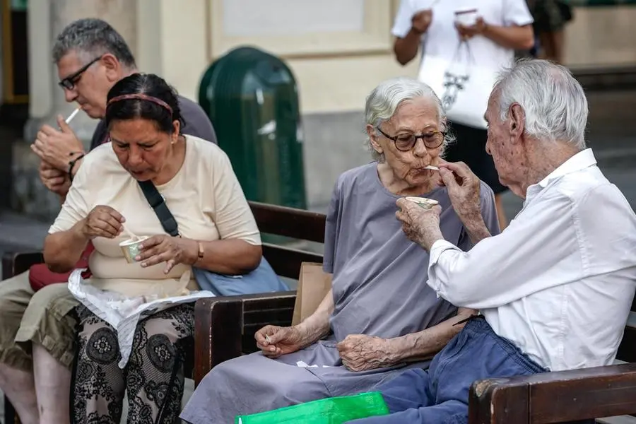Una coppia di anziani si rinfresca per combattere il grande caldo estivo mangiando un gelato in piazza Castello a Torino , ANSA