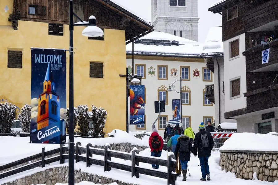 epa12702798 People walk past a banner reading \\\"Welcome to the 2026 Host City\\\" of the Milano Cortina 2026 Winter Olympic Games, in Cortina d'Ampezzo, Italy, 03 February 2026. EPA/JEAN-CHRISTOPHE BOTT