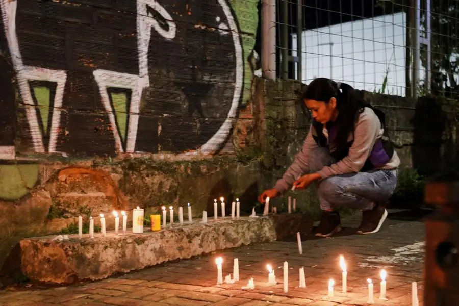 Una donna accende una candela in una strada di Manizales.