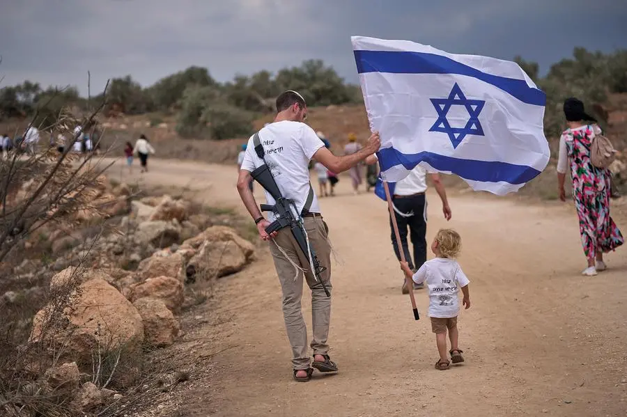 Israeli settlers walk along the road between Ganim and Kadim as they celebrate the inauguration of the newly built illegal Kadim outpost in the occupied West Bank, Wednesday, Sept. 30, 2026. (AP Photo/Ohad Zwigenberg)