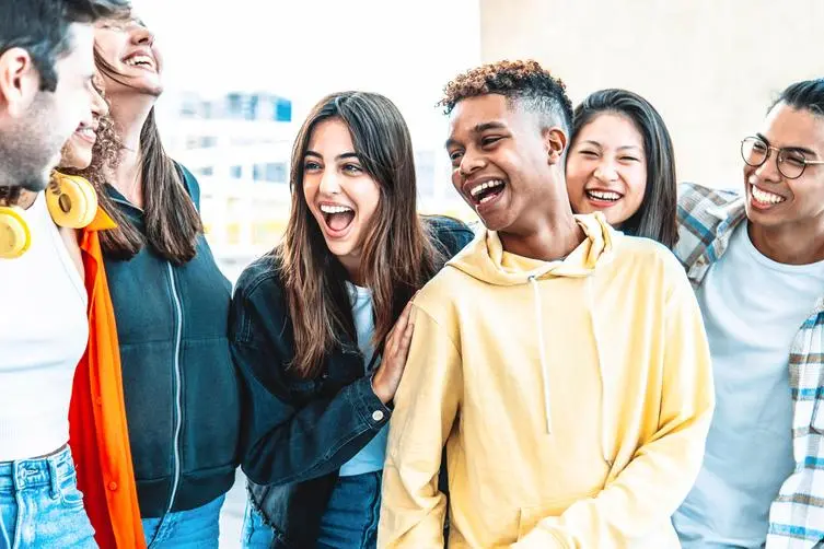 Multicultural best friends having fun hanging out together - Happy young people laughing walking on city street - International students talking outside school in college campus - Friendship concept