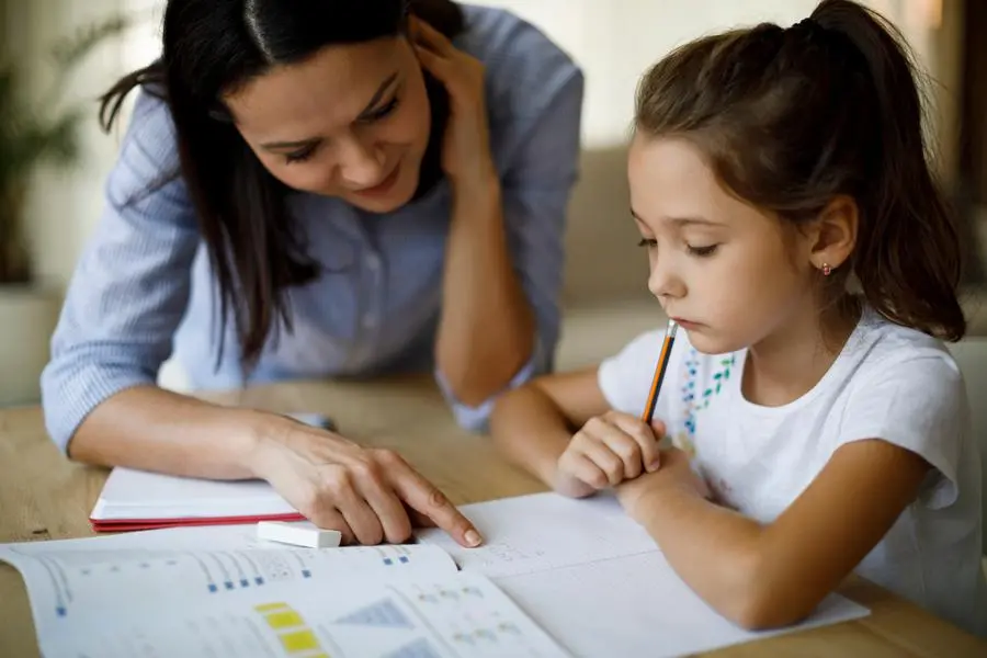 Mother and daughter working homework together , Getty Images