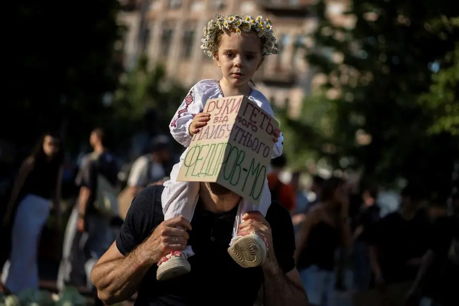 Un uomo con una bambina sulle spalle nella manifestazione di protesta a Kyiv contro la destituzione di Fedorov.