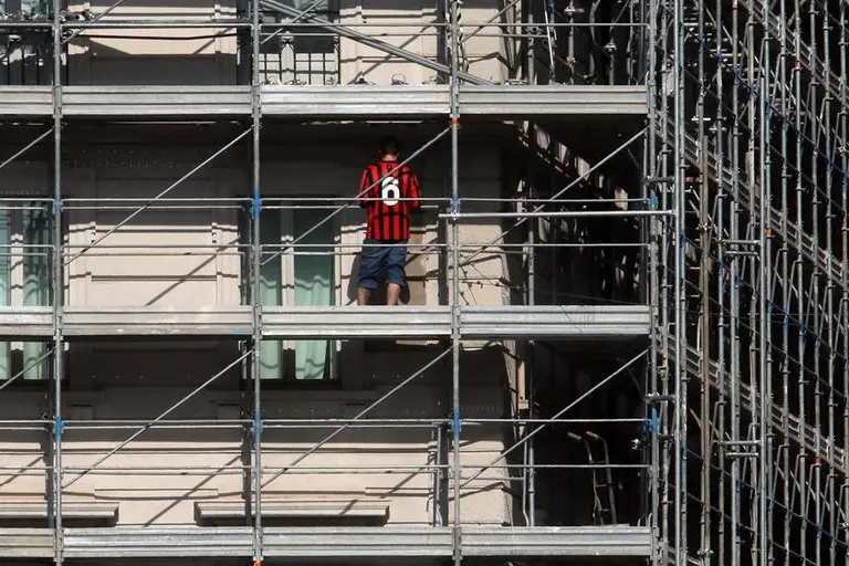 Un operaio al lavoro con la maglia di Franco Baresi in un cantiere vicino alla Basilica di Sant\\'Ambrogio dove si tengono i funerali di Franco Baresi. Milano 4 Agosto 2026 , ANSA