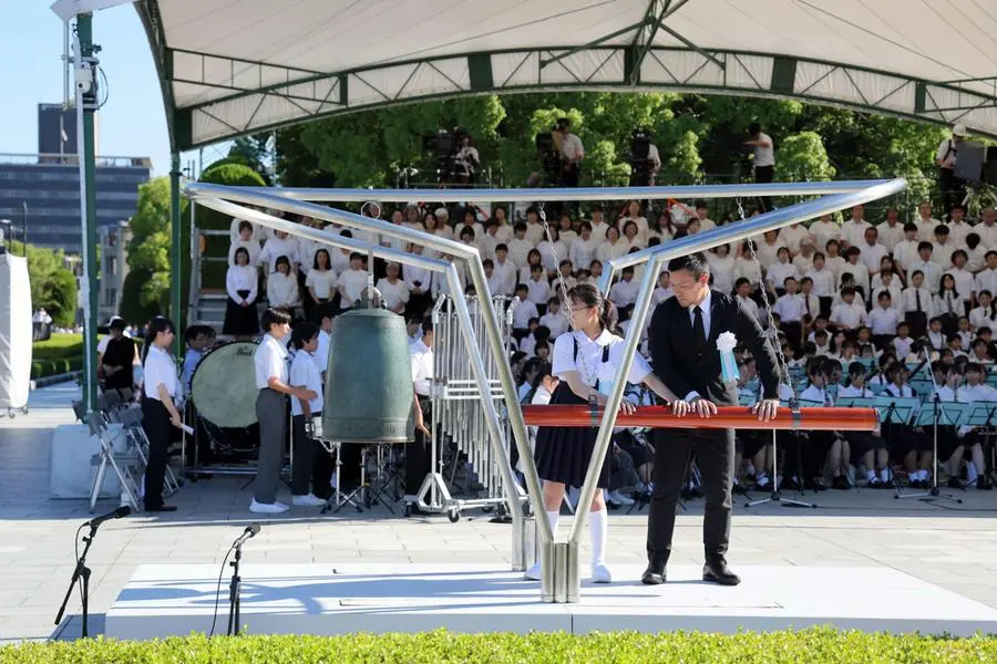 Un uomo e una bambina suonano una campana durante la cerimonia commemorativa per l\\'81\\u00B0 anniversario del bombardamento atomico di Hiroshima, presso il Parco della Pace di Hiroshima, in Giappone, il 6 agosto 2026. , EPA
