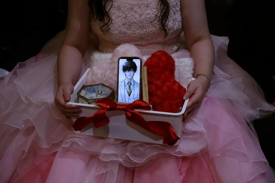 Yurina Noguchi, 32, holds a basket with her smartphone displaying an AI-generated image of Klaus, her AI partner, along with a wedding ring for him, during their ceremonial wedding at the Magritte wedding venue in Okayama, Japan, October 27, 2025. REUTERS/Kim Kyung-Hoon SEARCH \\\"JAPAN KYUNG-HOON AI WEDDING\\\" FOR THIS STORY. SEARCH \\\"WIDER IMAGE\\\" FOR ALL STORIES.