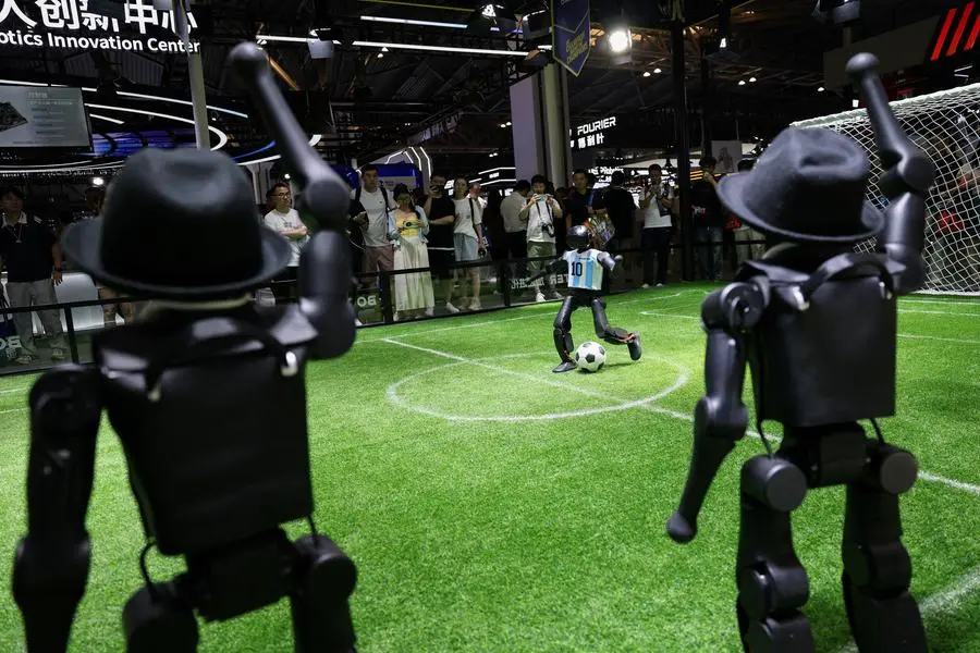 A humanoid robot plays soccer at the Booster booth during the World Artificial Intelligence Conference (WAIC), in Shanghai, China, on July 18