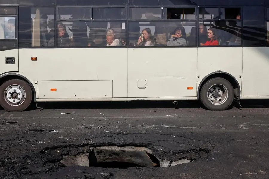 Abitanti di Kyiv a bordo di un autobus passano accanto al punto del Ponte Nord colpito da un drone russo il 4 ottobre. , REUTERS