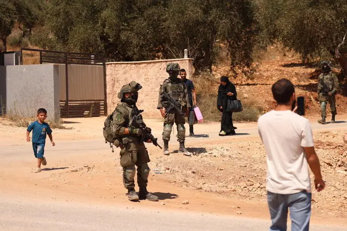 epa13166056 Israeli soldiers observe Palestinians during a raid in the town of Qusra, south of Nablus, West Bank, 13 August 2026. The Israeli army entered Qusra following days of a settler siege on Palestinian homes and declared the area a closed military zone to dismantle the illegal settler outpost while forcing local residents out of their homes to set up military posts. EPA/ALAA BADARNEH