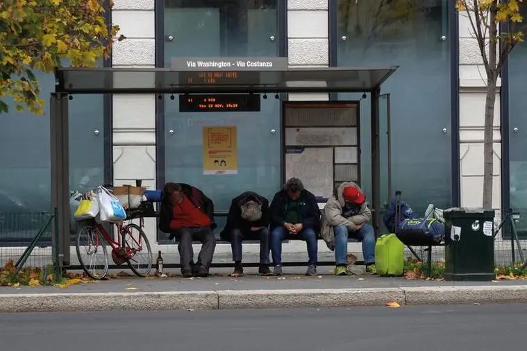 Europa, Italia, Milano novembre 2020 - quattro senzatetto che dormono in una fermata dell'autobus durante il blocco del Coronavirus Covid-19 nel centro della città - emergenza povertà e disoccupazione - Via Washinton