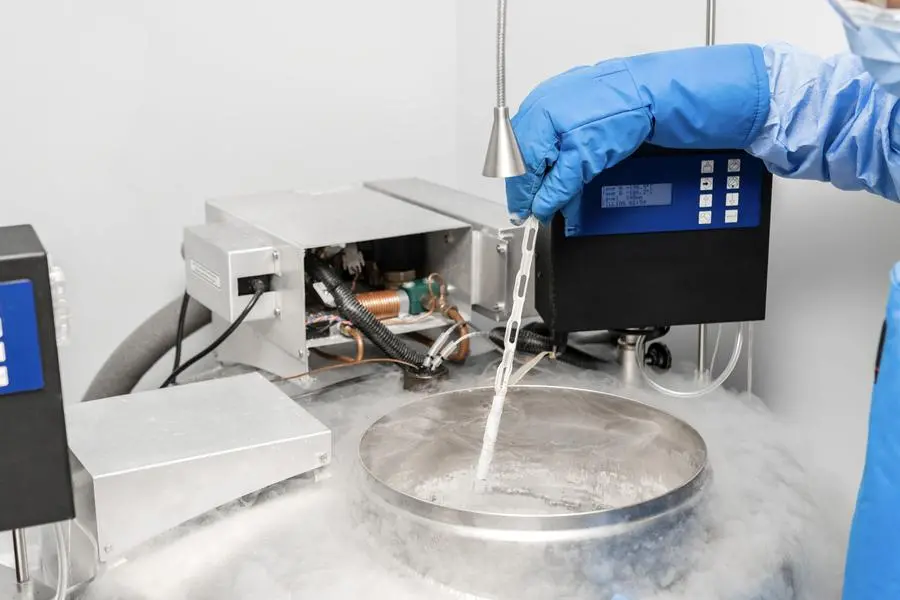 Embryologist in blue gloves using liquid nitrogen for cryopreservation of embryos and eggs in IVF lab, vitrification process in fertility clinic for assisted reproductive technology and pregnancy.