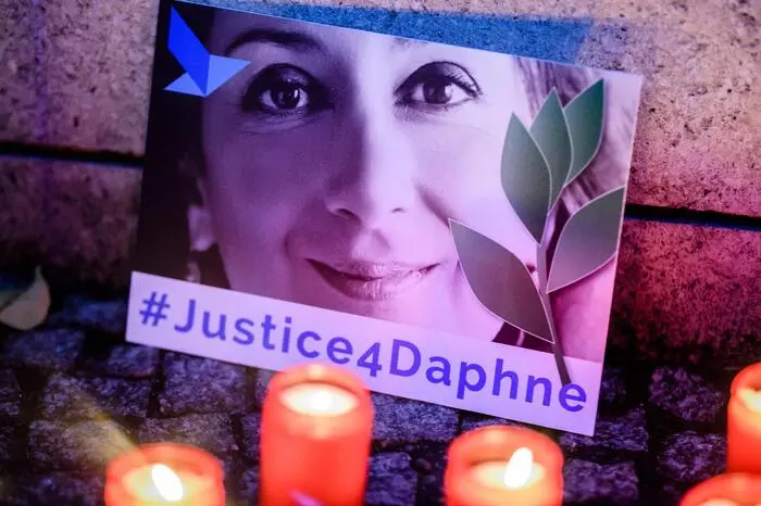 epa07925848 'Justice four Daphne' is written on a cardboard showing a photo of Daphne Caruana Galizia, during a picket in front of the Maltese embassy for murdered journalist Daphne Caruana Galizia in Berlin, Germany, 16 October 2019. Reporters Without Borders organized a picket for murdered journalist Daphne Caruana Galizia, who was killed on 16 October 2017 in Malta, while investigating the Panama Papers case. EPA/CLEMENS BILAN