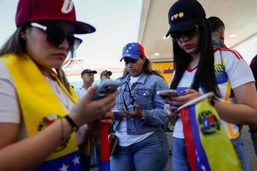 Venezuelani leggono le notizie sugli smartphone dopo la cattura di Maduro da parte delle forze statunitensi , REUTERS
