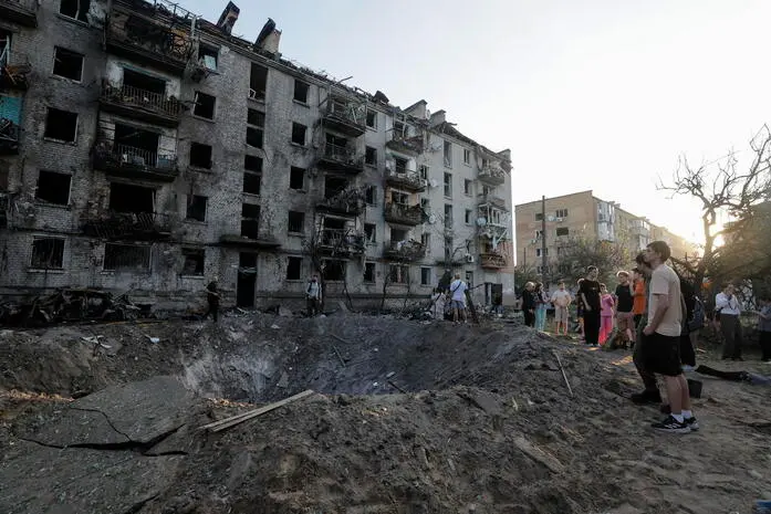 epaselect epa13079504 Local people look at a crater at the site of a Russian missile strike on a residential area in Kyiv, Ukraine, 02 July 2026, amid the Russian invasion. At least 13 people died and more than 90 were injured after a massive combined Russian attack overnight in Kyiv, according to the State Emergency Service. Russia used about 500 drones and more than 70 missiles of different types during the massive combined attack on Ukraine, as the air forces reported. Kyiv was the main direction of the attack. EPA/SERGEY DOLZHENKO