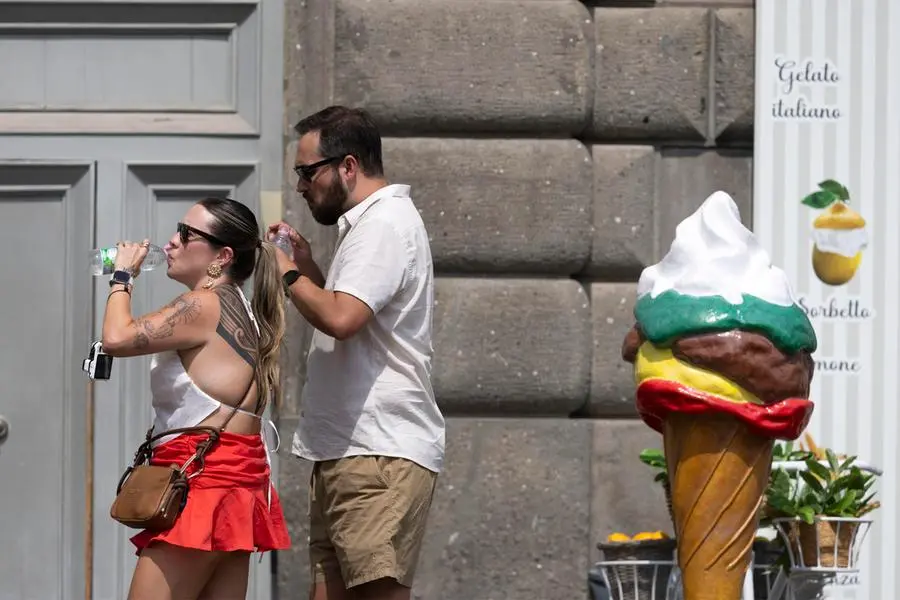 Turisti si proteggono dal caldo bevendo e utilizzando degli ombrelli al centro storico della Capitale. Roma, 24 giugno 2026. ANSA/MASSIMO PERCOSSI (estate, temperatura, calore, generica, simbolica, riscaldamento globale) , ANSA