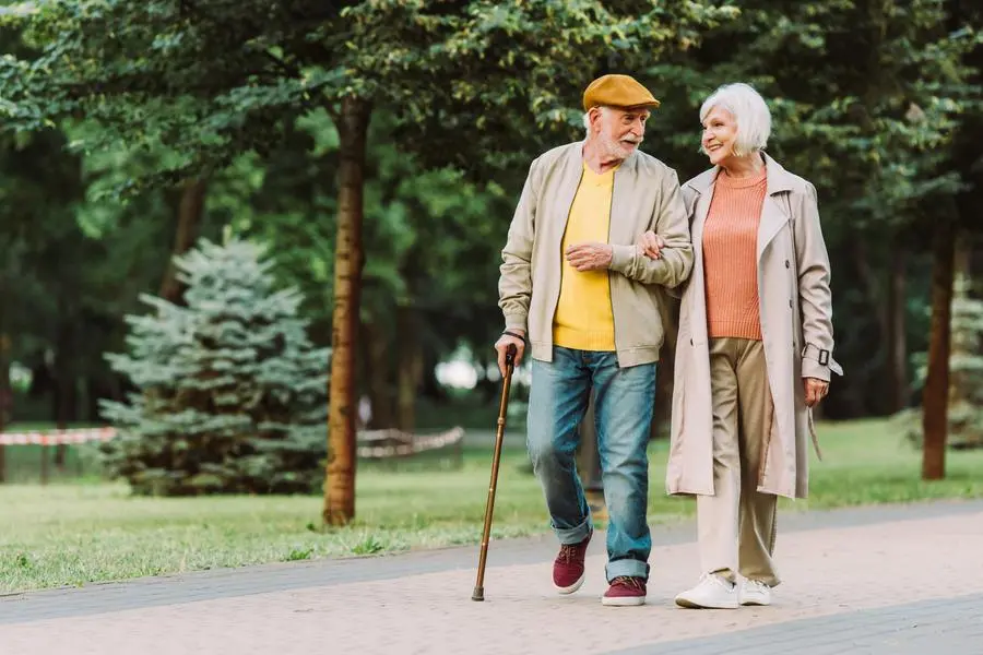 Senior couple smiling while walking on path in park