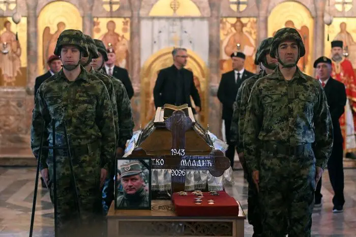 TOPSHOT - Serbian armed forces stand guard as Darko Mladic stands in front of the coffin of his father while taking part in a public memorial on the day of the funeral ceremony for late Bosnian Serb military leader Ratko Mladic at St Lukas church in Belgrade, on September 7, 2026. Mladic, 84, died last week after suffering several strokes while serving a life sentence in The Hague for war crimes committed during the 1990s war in Bosnia. (Photo by OLIVER BUNIC / AFP)