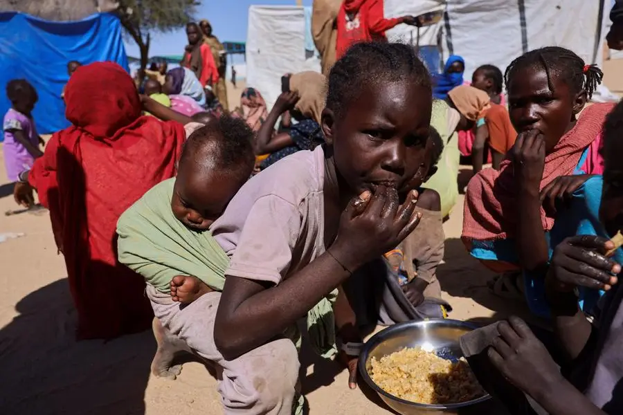 Bambini rifugiati sudanesi provenienti da Al-Fashir condividono un pasto da un unico piatto nel campo di transito di Tin\\u00E9, nell\\u2019est del Ciad, mentre prosegue il conflitto tra le Forze di Supporto Rapido (RSF) e l\\u2019esercito sudanese. , REUTERS