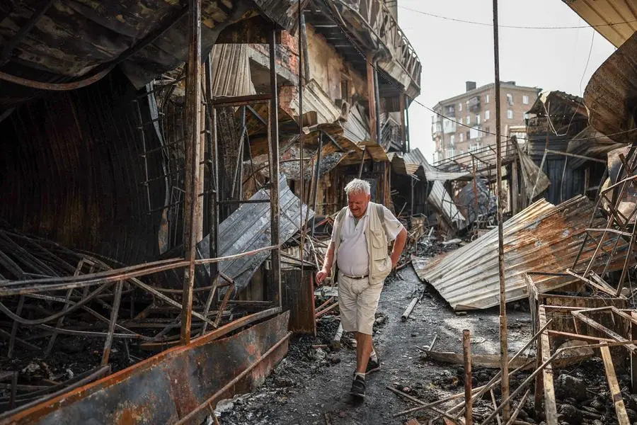 Un uomo passa fra le macerie di un mercato a Kyiv distrutto dall\\'attacco russo. , REUTERS